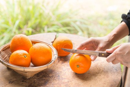 Téléchargez les photos : Femme coupant orange sur un couteau - en image libre de droit