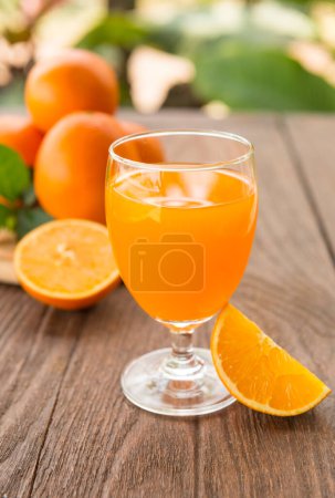 Photo for Glass of fresh orange juice with ripe oranges on a wooden table. - Royalty Free Image