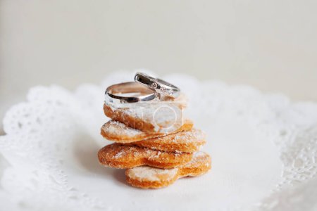 Foto de "Anillos de boda de oro con diamantes se encuentran en la pila de galletas dulces. Símbolo de amor y matrimonio
." - Imagen libre de derechos