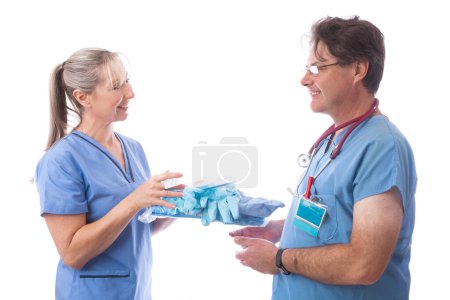 Photo for Hospital healthcare worker hands a PPE kit to another nurse - Royalty Free Image
