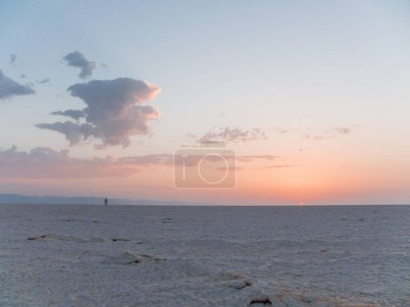 Photo for Man meets sunrise alone in Sahara desert. Salt crust on a desert surface. Egypt. - Royalty Free Image
