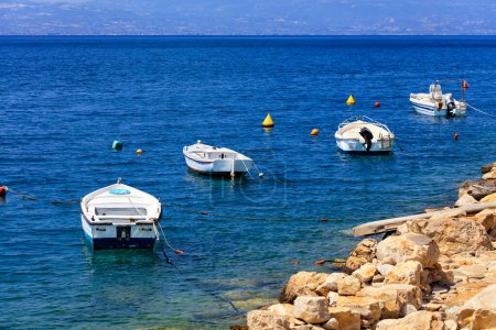 Foto de Barcos de motor y barcos están anclados a lo largo de la costa rocosa del mar Jónico
. - Imagen libre de derechos
