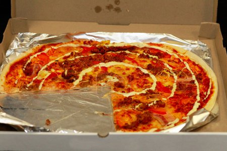 Téléchargez les photos : "Pizza dans une boîte avec un morceau cassé. Pizza du café. Une pizza. La pizza standard habituelle." - en image libre de droit