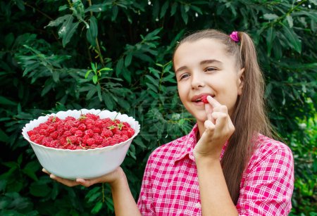 Photo for Teen girl holding a bowl of raspberries in the garden - Royalty Free Image