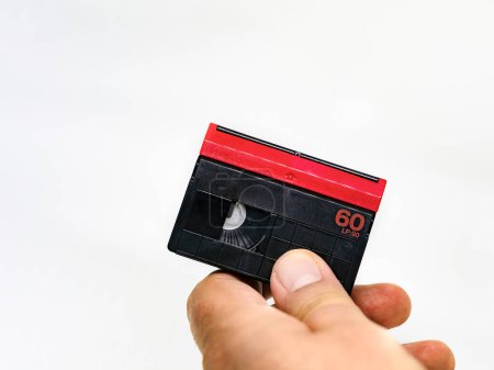 Téléchargez les photos : "main masculine tenant une cassette vidéo au format Mini DV isolée sur une " - en image libre de droit