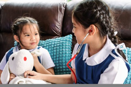 Téléchargez les photos : Deux petites filles sourient et jouent au docteur avec stéthoscope - en image libre de droit