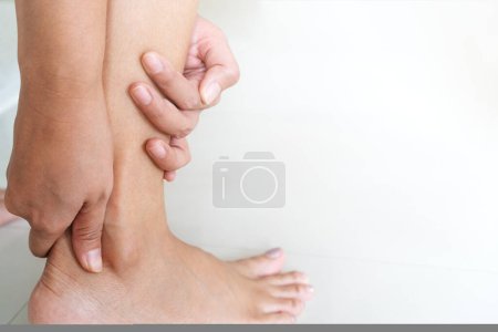 Téléchargez les photos : Femme massant ses jambes avec ses pieds. - en image libre de droit