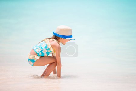 Téléchargez les photos : Petite fille à la plage de sable blanc tropical faisant château de sable - en image libre de droit
