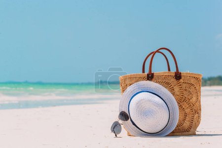 Foto de Accesorios de playa - bolsa de paja, sombrero y anteojos en la playa - Imagen libre de derechos