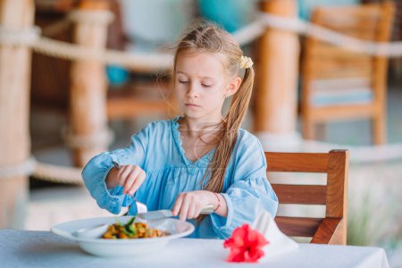 Photo for "Adorable little girl having dinner at outdoor cafe" - Royalty Free Image