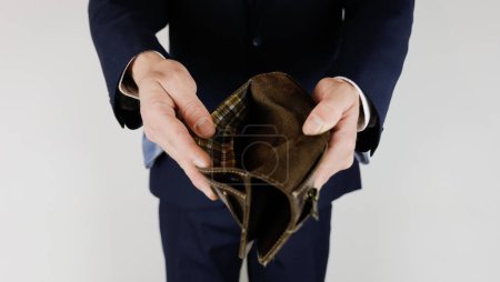 Foto de Un hombre con traje de negocios tiene en sus manos una cartera vacía - Imagen libre de derechos