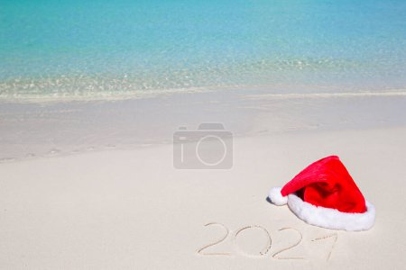 Photo for 2021 written on tropical beach white sand with xmas hat - Royalty Free Image