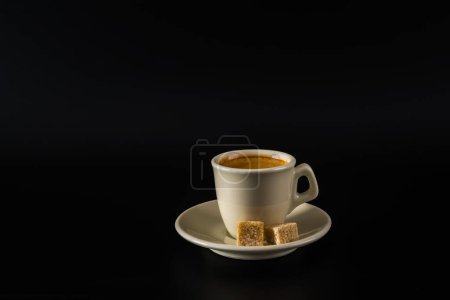 Foto de Café negro aromático en una taza blanca, azúcar morena, fondo negro - Imagen libre de derechos