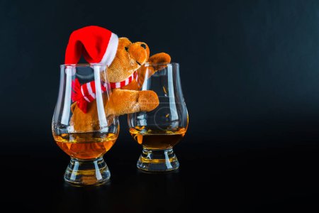 Photo for "Christmas teddy bear with glasses of single malt whiskey, symbol o" - Royalty Free Image