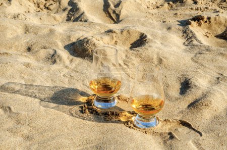 Foto de Vasos de whisky en la playa de arena - Imagen libre de derechos