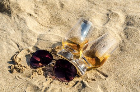 Téléchargez les photos : Lunettes de whisky single malt sur la plage de sable - en image libre de droit