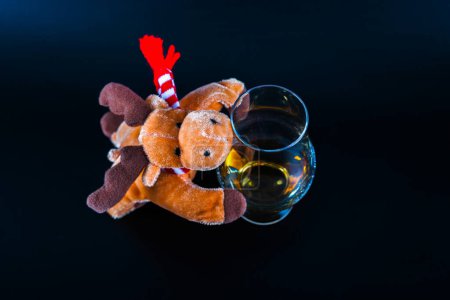 Foto de Reno de peluche Rudolph con un whisky de malta en vidrio, símbolo de la Navidad - Imagen libre de derechos