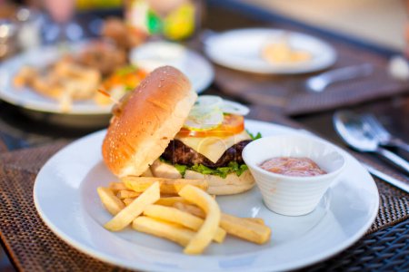 Photo for Classic burger with French fries on table in outdoor cafe - Royalty Free Image