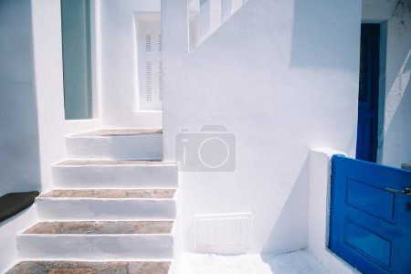 Photo for The narrow streets of the island with blue balconies, stairs and flowers in Greece. - Royalty Free Image