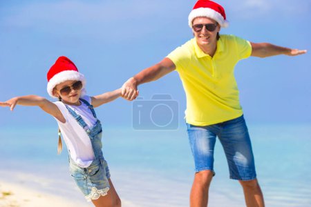 Photo for Little girl and happy father in Santa Hats enjoy Christmas vacation - Royalty Free Image