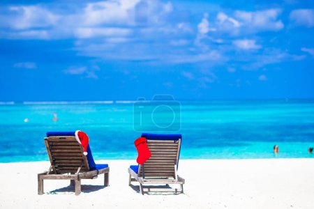Foto de Red Christmas media y Santa Sombrero en silla en la playa tropical blanca - Imagen libre de derechos