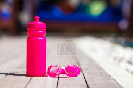 Photo for Pink sporty water bottle near swimming pool - Royalty Free Image