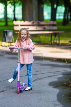 Foto de Adorable niña se divierten en el scooter al aire libre - Imagen libre de derechos