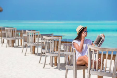Téléchargez les photos : Fille heureuse lisant sur la plage blanche tropicale - en image libre de droit