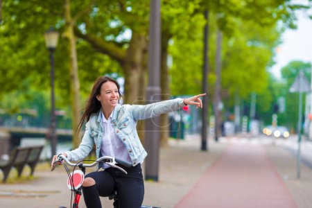Photo for Young happy woman on bike in european city - Royalty Free Image