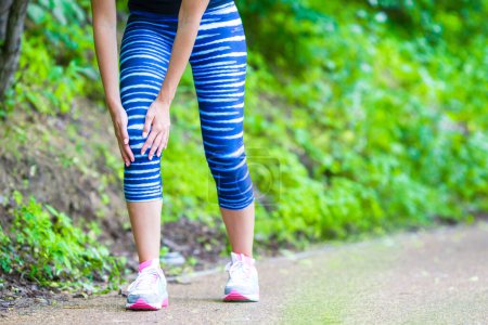 Téléchargez les photos : Athlète féminine souffrant de douleur à la jambe pendant l'exercice à l'extérieur - en image libre de droit