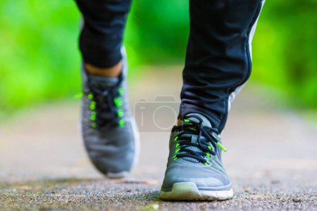 Téléchargez les photos : Gros plan sur la chaussure d'athlète coureur homme pieds en cours d'exécution sur la route - en image libre de droit