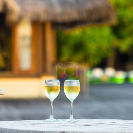 Photo for "Two glasses of tasty white wine at sunset on wooden table" - Royalty Free Image