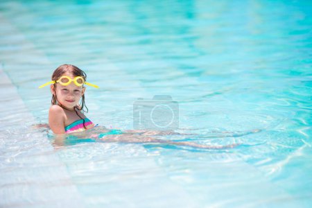 Téléchargez les photos : Petite fille adorable heureuse dans la piscine extérieure - en image libre de droit