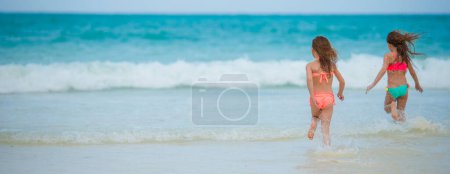 Foto de Niñas divirtiéndose en la playa tropical jugando juntas en aguas poco profundas - Imagen libre de derechos