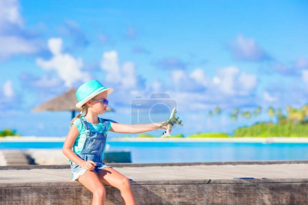 Téléchargez les photos : Petite adorable fille avec grande valise rose et carte de l'île sur la plage blanche - en image libre de droit