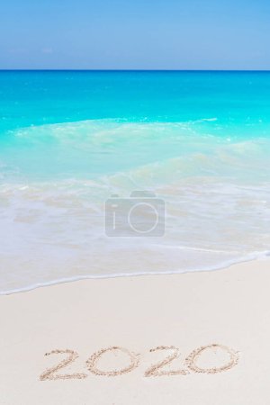 Photo for Year 2020 hand written on the white sand in front of the sea - Royalty Free Image