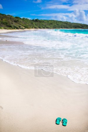 Photo for Summer mint flip flops with sunglasses on white beach - Royalty Free Image