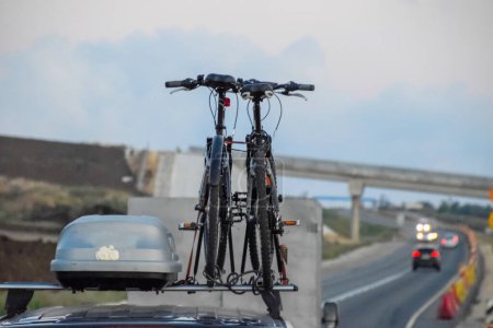 Téléchargez les photos : Vélos attachés au toit de la voiture. Voyager en vélo en voiture. - en image libre de droit