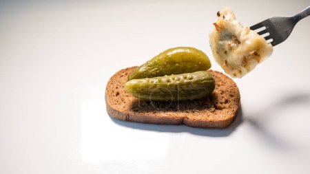 Téléchargez les photos : "boulette sur une fourchette comestible sur un fond blanc concombre sur une table avec du pain" - en image libre de droit
