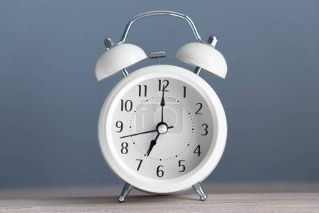 Foto de Reloj despertador sobre mesa de madera con fondo gris - Imagen libre de derechos