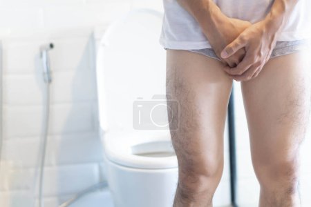 Téléchargez les photos : "Gros plan homme tenant la vessie avec la douleur de pipi dans les toilettes - en image libre de droit