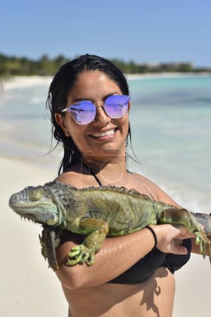Foto de Chica mexicana en gafas de sol con iguana en la playa - Imagen libre de derechos