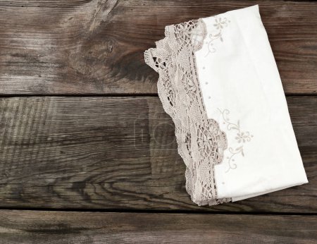 Foto de Toalla de encaje textil de cocina blanca doblada sobre una mesa de madera gris - Imagen libre de derechos