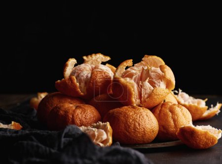 Téléchargez les photos : Tas de mandarines rondes mûres dans une assiette sur une serviette en textile noir - en image libre de droit