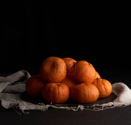 Téléchargez les photos : Pile de mandarine mûre ronde non pelée dans une assiette - en image libre de droit