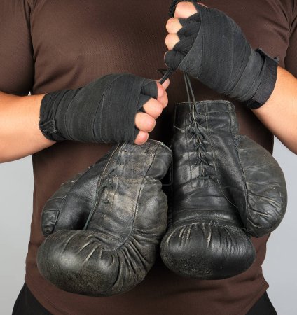 Téléchargez les photos : Athlète en vêtements marron tient très vieux vintage boxe en cuir - en image libre de droit