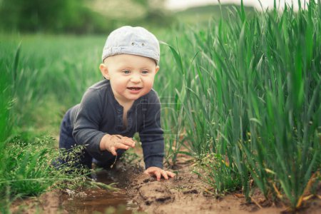 Photo for A Caucasian infant climbs in a muddy puddle - Royalty Free Image