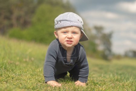 Téléchargez les photos : Un bébé de 11 mois grimpe sur la pelouse. - en image libre de droit