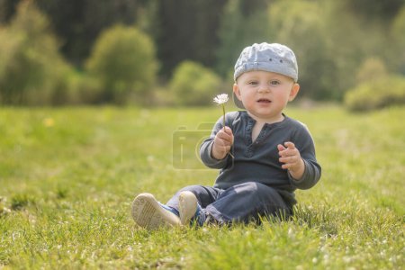 Téléchargez les photos : Caucasien bébé donnant une marguerite à la caméra - en image libre de droit