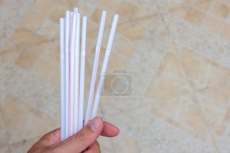 Photo for "Hand holding household plastic straws symbolizing plastic pollut" - Royalty Free Image